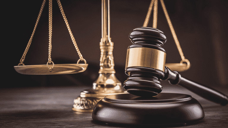 Scales of justice next to a gavel on a desk.