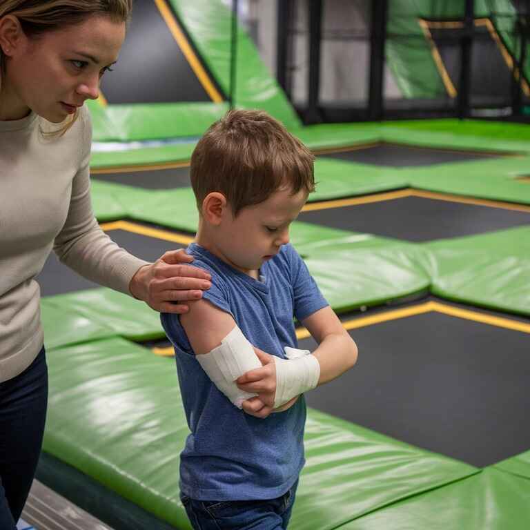 Parent and child leaving trampoline park after injury, with the child wearing a bandage